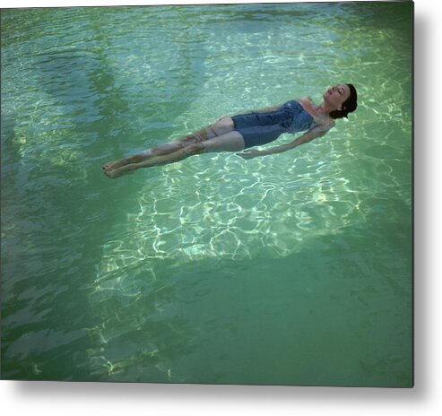 Exterior Metal Print featuring the photograph A Model Floating In A Swimming Pool by John Rawlings