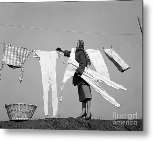 1940s Metal Print featuring the photograph Woman Removing Frozen Clothes by Debrocke/ClassicStock