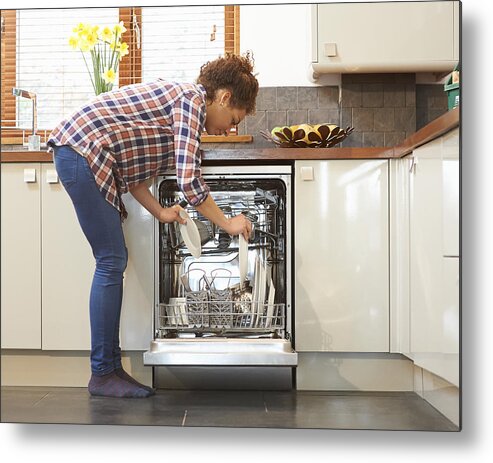 People Metal Print featuring the photograph Woman unloading dish washer in kitchen. by Dougal Waters