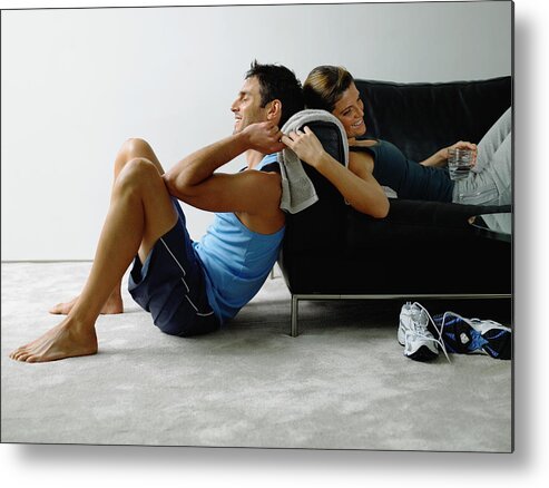 Heterosexual Couple Metal Print featuring the photograph Couple wearing sports clothes resting in living room, smiling by Michael Blann