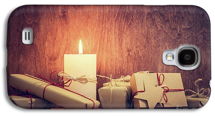 Christmas Galaxy S4 Case featuring the photograph Chistmas presents, gifts with a candle glowing on wooden wall background. by Michal Bednarek