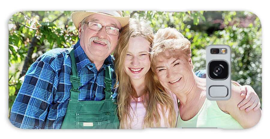 Family Galaxy Case featuring the photograph Granddaughter hugging grandparents in a summer garden. by Michal Bednarek