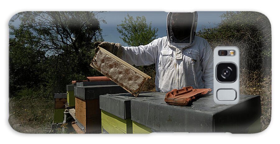 Side View Galaxy Case featuring the photograph A Beekeeper Is Holding A Frame Near Multiple Beehives by Cavan Images