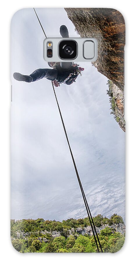 Man Galaxy Case featuring the photograph Low Angle View Of Man Rappelling From Mountain Against Sky by Cavan Images