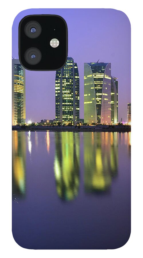 Tranquility iPhone 12 Case featuring the photograph 4 Skyscrapers Glow At Night Over The by Photography By Azrudin