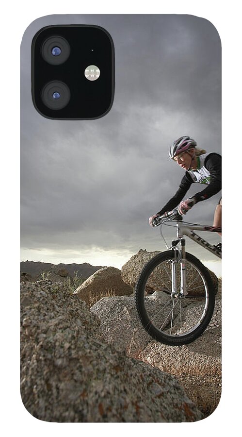 Sports Helmet iPhone 12 Case featuring the photograph Female Rider Mountain Biking Between by Thomas Northcut