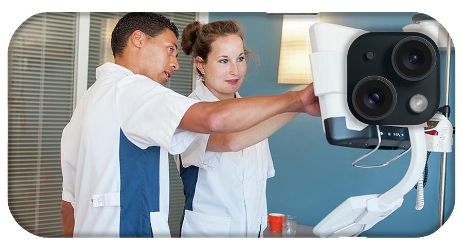 Indoors iPhone Case featuring the photograph Two Nurses Checking Monitor On Hospital Bed by Arno Massee/science Photo Library
