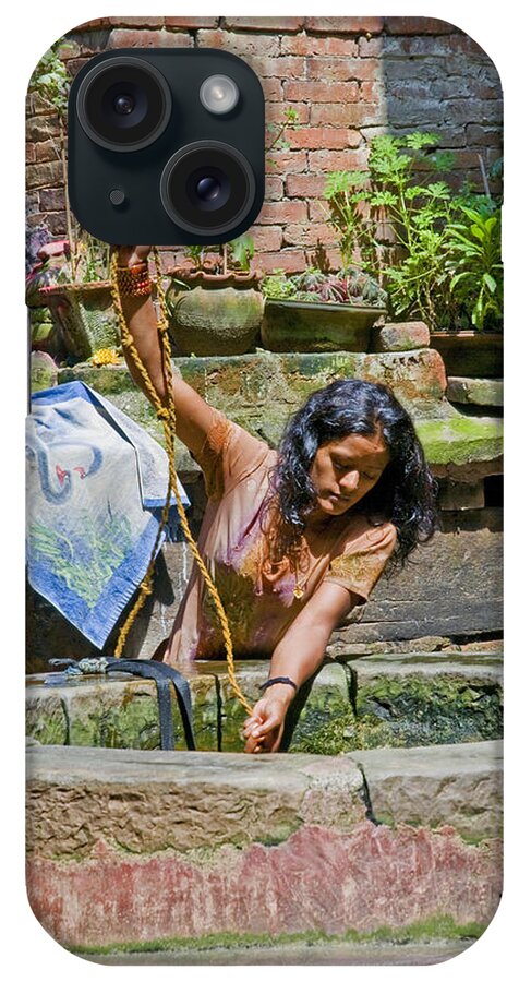 Well iPhone Case featuring the photograph A woman draws water at a well in Bhaktapur Nepal by Christopher Byrd