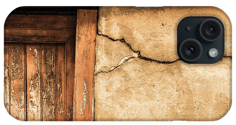 Foix iPhone Case featuring the photograph Cracked lime stone wall and detail of an old wooden door by Semmick Photo