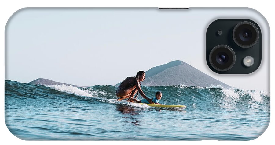 Portrait iPhone Case featuring the photograph Pulled Back View Of Mother And Son Surfing A Small Wave by Cavan Images