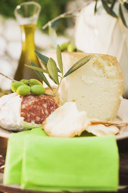 Antipasti Poster featuring the photograph Cheese, Salami, Olives, Crackers, Olive Oil On Outdoor Table by Foodcollection