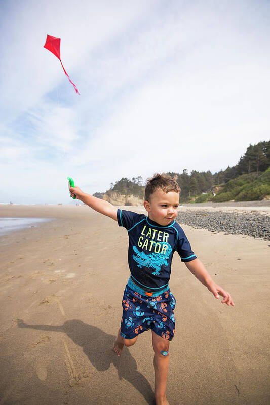 Movement Poster featuring the photograph Young Boy Running Kite Along The Beach With Determination. by Cavan Images