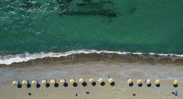 Summertime Poster featuring the photograph Aerial view from a flying drone of beach umbrellas in a row on an empty beach with braking waves. by Michalakis Ppalis