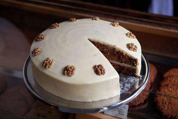 Unhealthy Eating Poster featuring the photograph A Carrot Cake On A Display Cabinet In A by Halfdark