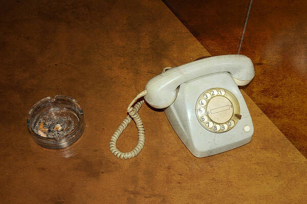 Phone Poster featuring the photograph Old telephone and ashtray on brown table by Matthias Hauser