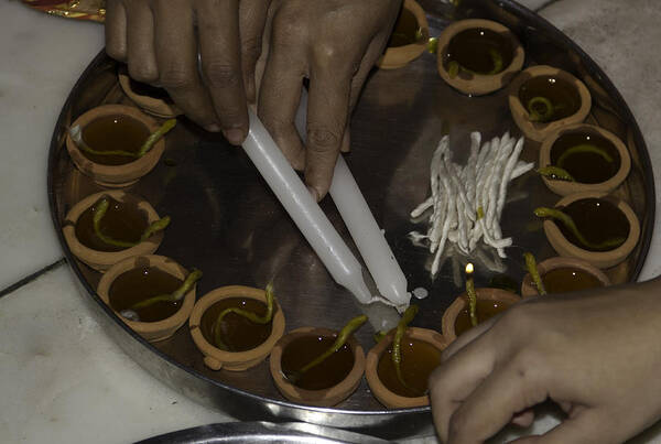 Celebrating Poster featuring the photograph Starting to light lamps in a plate using candles by Ashish Agarwal