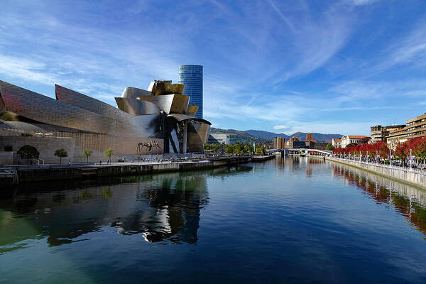 Spain Bilbao Guggenheim Museum Basque Country Frank Gehry Contemporary Architecture Nervion River City Daring And Innovative Curves Building Exterior Spectacular Building Deconstructivism Ferrovial Clad In Glass Poster featuring the photograph Bilbao in autumn with blue skies next to the river Nervion by Andy Myatt