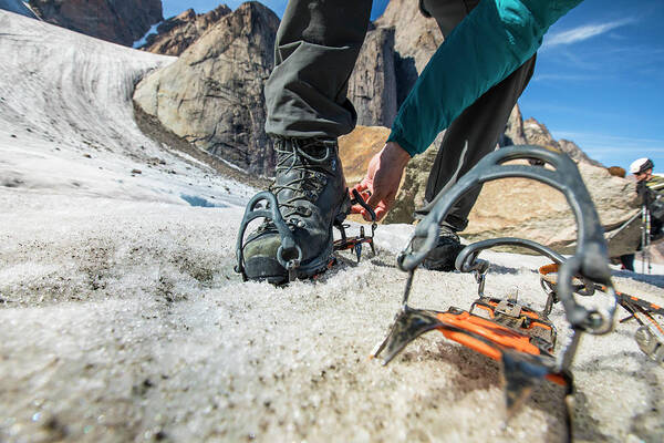 Climber Straps On Crampons To His Mounatineering Boots On Glacier