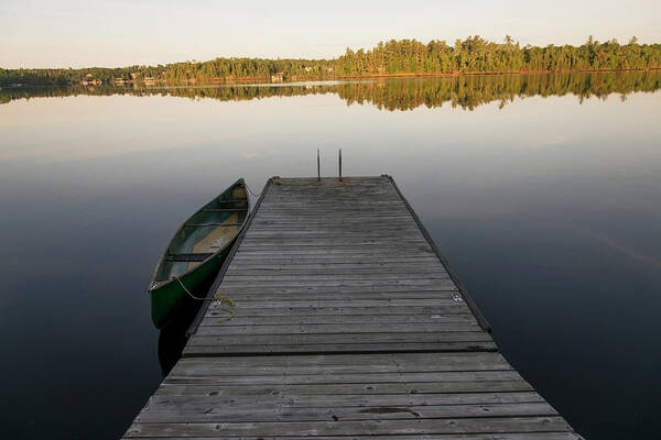 Tranquility Poster featuring the photograph A Canoe Tied To A Wooden Dock On A by Keith Levit / Design Pics