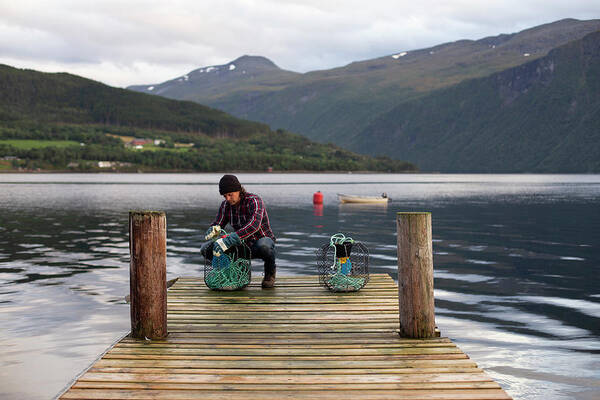 Male Poster featuring the photograph A Norwegian Working On Some Crab Pots On A Dock By The Fjord by Cavan Images