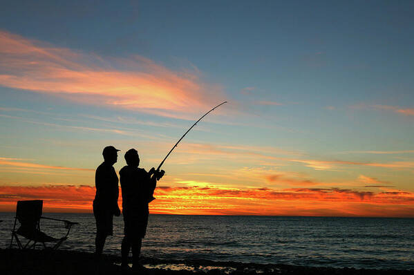 A Silhouette Of Two Men Fishing At Poster by Jamesbowyer 