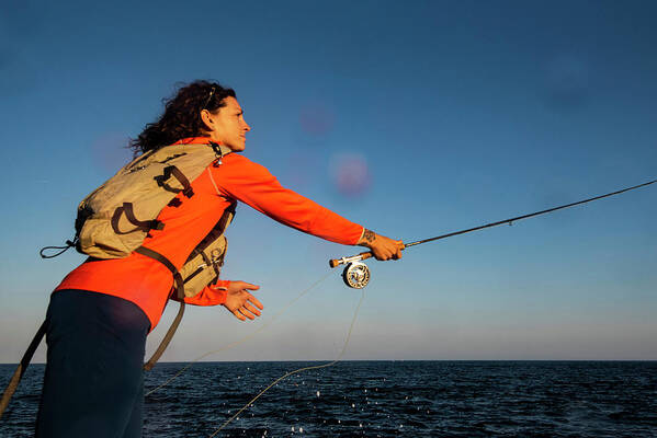 Aurora Photos Poster featuring the photograph A Woman Casting A Fly Rod Along The Coast Of Maine by Cavan Images