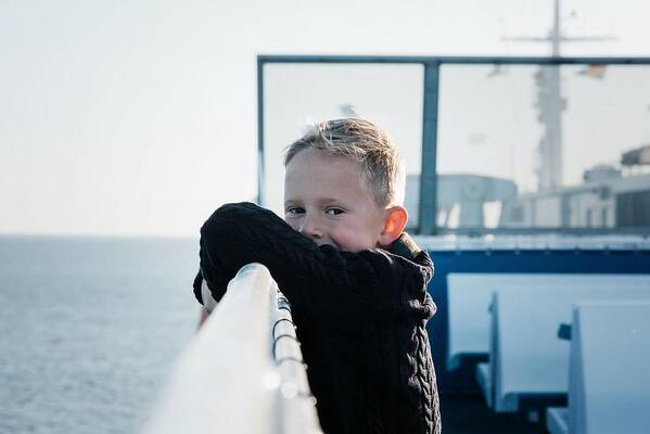 Boat Poster featuring the photograph Portrait Of A Young Boy On A Ferry Looking Happy And Relaxed At Sea by Cavan Images