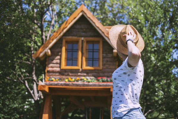 Woman Poster featuring the photograph Woman With Straw Hat Looking At Wooden Cabin by Cavan Images
