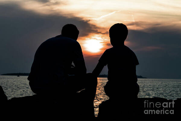Adult Poster featuring the photograph Father And Son Talking While Sitting On Stones At The Coast During Sunset by Andreas Berthold