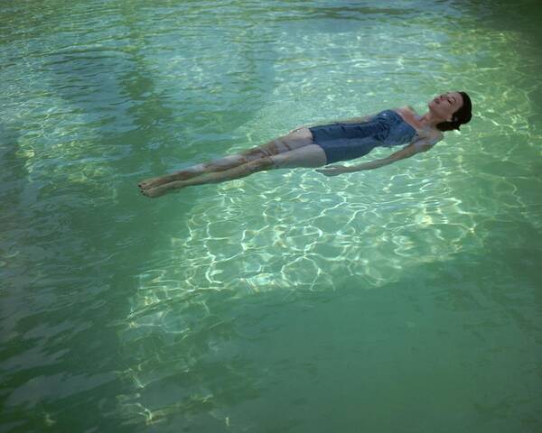 Exterior Poster featuring the photograph A Model Floating In A Swimming Pool by John Rawlings