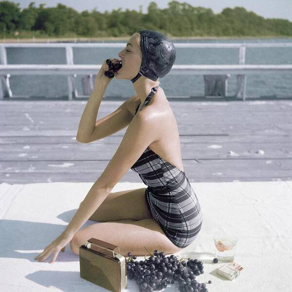 Water Poster featuring the photograph A Young Woman Wearing A Swimsuit Eating Grapes by John Rawlings