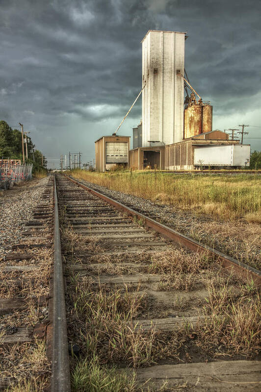 Grain Elevator Art Print featuring the photograph Foreboding Sky Above a Prairie Sentinel - Storm - Railroad Tracks by Jason Politte