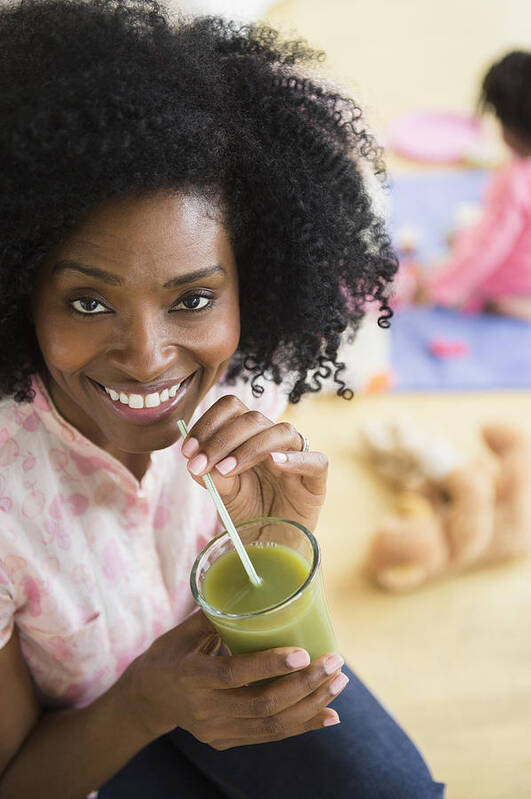 Three Quarter Length Art Print featuring the photograph Smiling woman drinking green juice by JGI/Jamie Grill