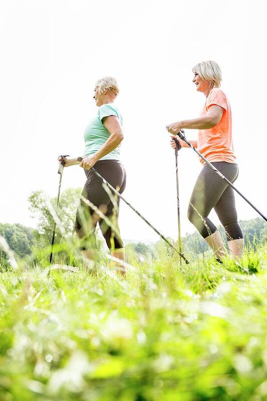 Two People Art Print featuring the photograph Two Women Walking In Grass With Walking Poles by Science Photo Library