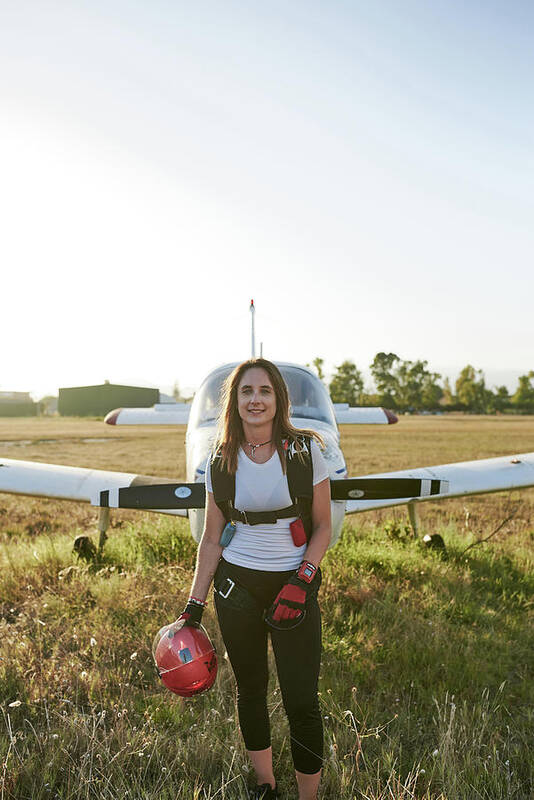 Skydivers Art Print featuring the photograph Young Female Skydiver In An Airfield With A Plane Behind Her #2 by Cavan Images