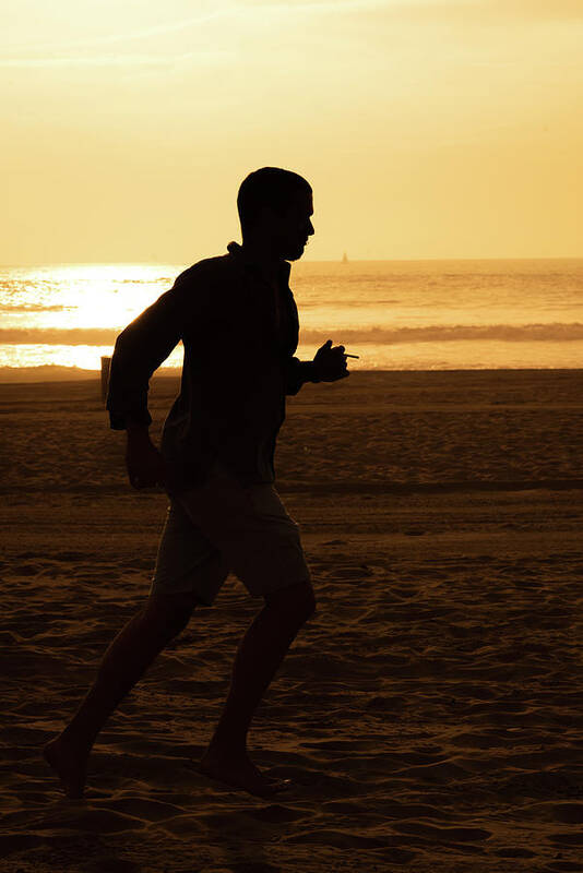 Silhouette Art Print featuring the photograph Silhouette of a tall man running on beach at sunset stock photo by Mark Stout