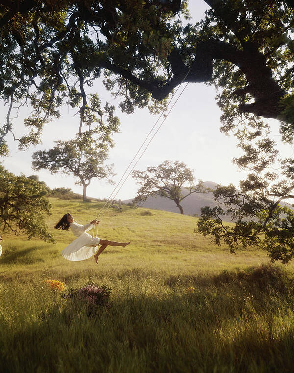 Grass Art Print featuring the photograph Young Woman Swinging On Rope Swing Tied by Tom Kelley Archive