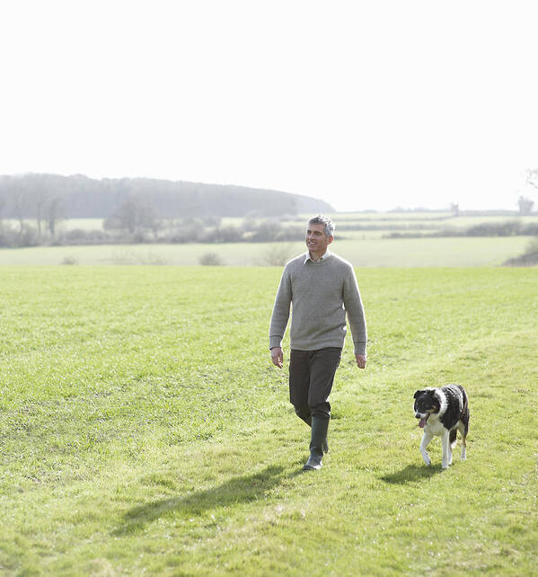 Pets Art Print featuring the photograph Man walking in countryside with pet dog by Dougal Waters