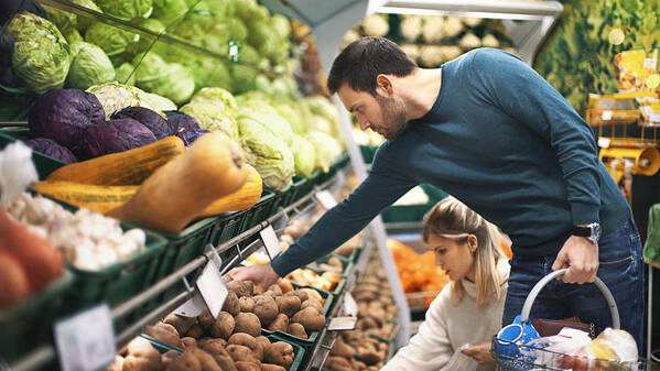 Heterosexual Couple Art Print featuring the photograph Couple in supermarket buying vegetables. by Gilaxia