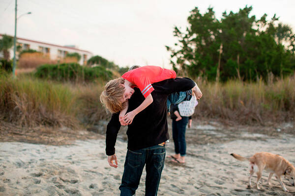 Wrightsville Beach Art Print featuring the photograph A Man Carries His Son Over His Shoulder by Logan Mock-Bunting
