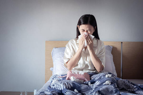 Cold And Flu Art Print featuring the photograph Asian woman have a cold, sitting on cozy bed using tissue for snot. sick at home by Asiandelight