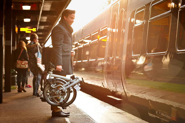 People Art Print featuring the photograph Businessman with folding cycle boarding train by Dean Mitchell