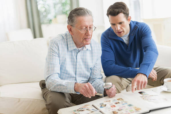 Three Quarter Length Art Print featuring the photograph Caucasian father and son examining stamp collection by JGI/Tom Grill