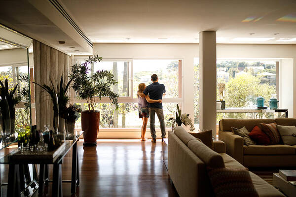 Heterosexual Couple Art Print featuring the photograph Couple admiring the view from the living room of their house. by Capuski