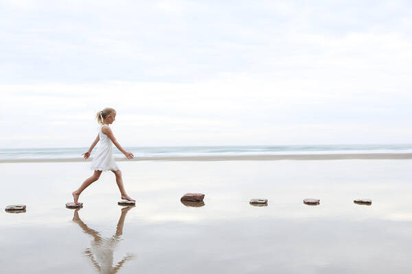 Hand Raised Art Print featuring the photograph Girl on stepping stones on beach by Peter Cade