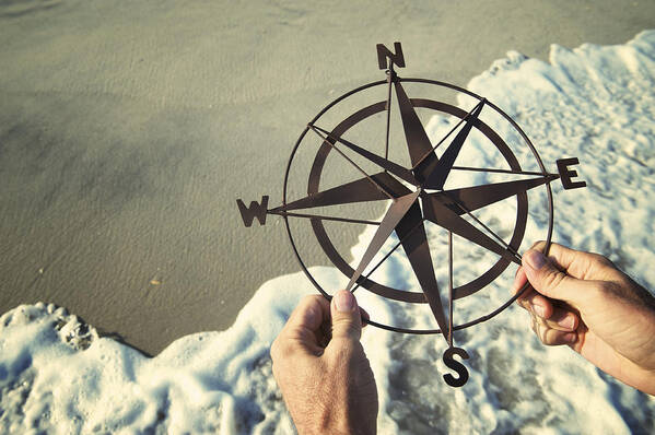Water's Edge Art Print featuring the photograph Hands Holding Compass Over Waves Rushing on Beach by PeskyMonkey