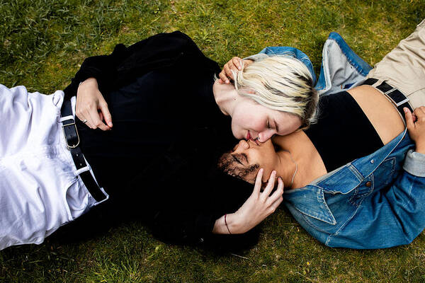 Grass Art Print featuring the photograph LGBT couple lying in the grass kissing by Sophie Mayanne