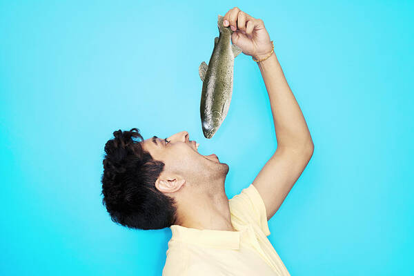 Hand Raised Art Print featuring the photograph Man Eating Whole Fish by Tara Moore