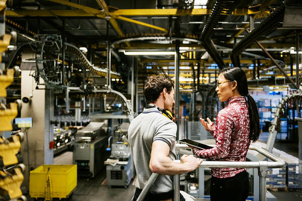 Asian And Indian Ethnicities Art Print featuring the photograph Mechanic And Female Engineer Talking in Factory by TommL