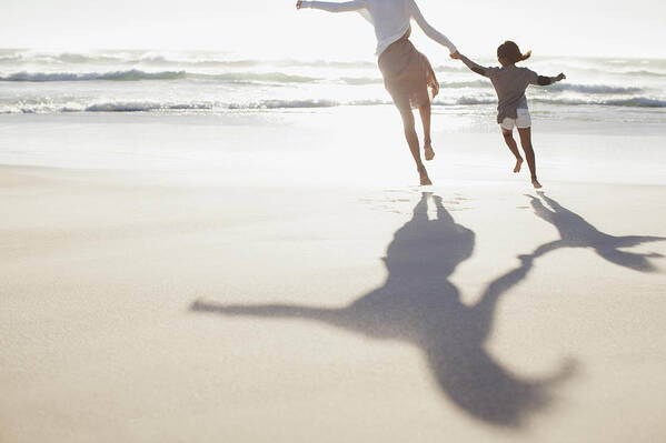 Shadow Art Print featuring the photograph Mother and daughter holding hands and running on sunny beach by Sam Edwards